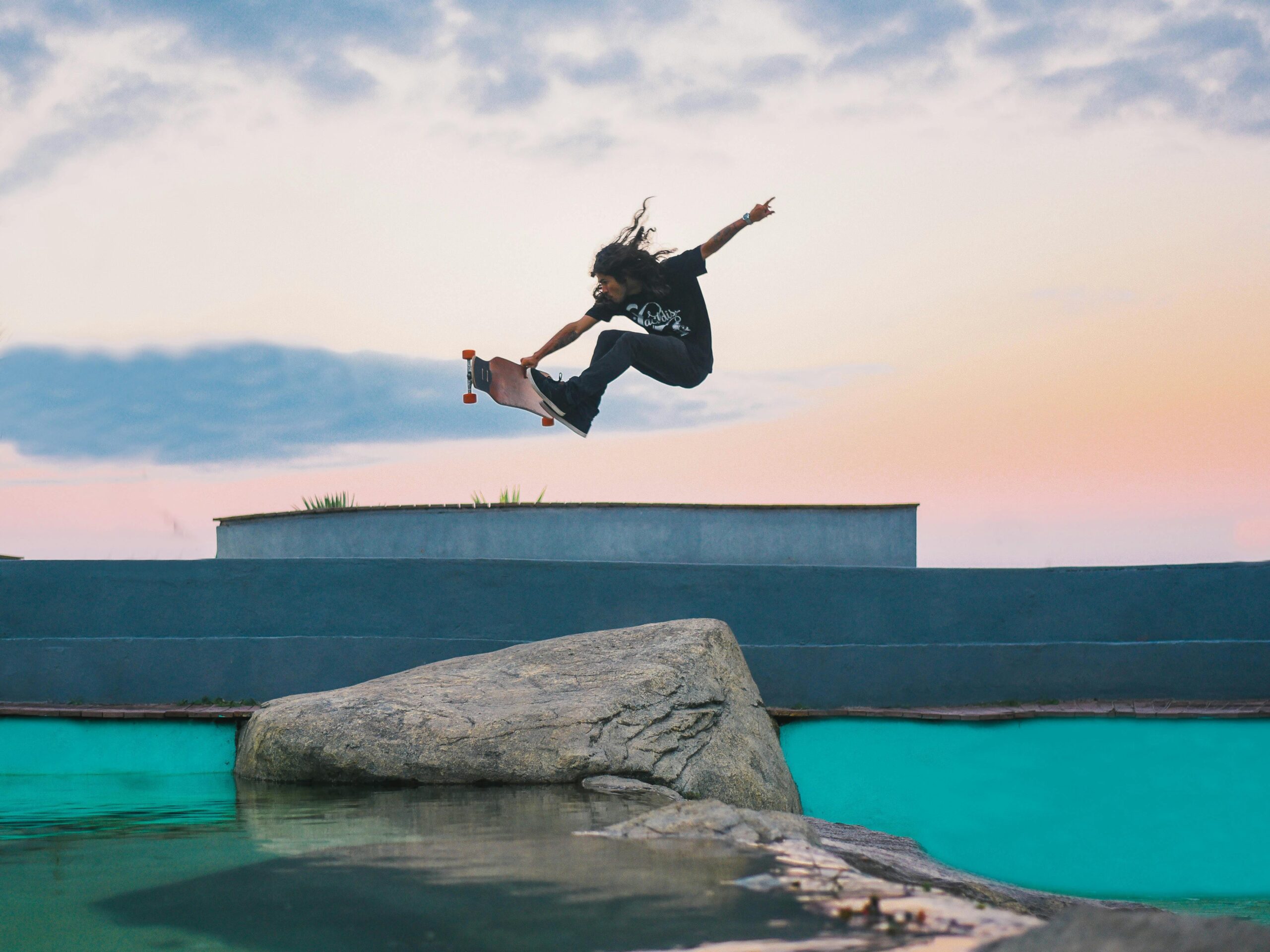 Dynamic shot of a skateboarder mid-air against a sunset backdrop, showcasing skill and style.